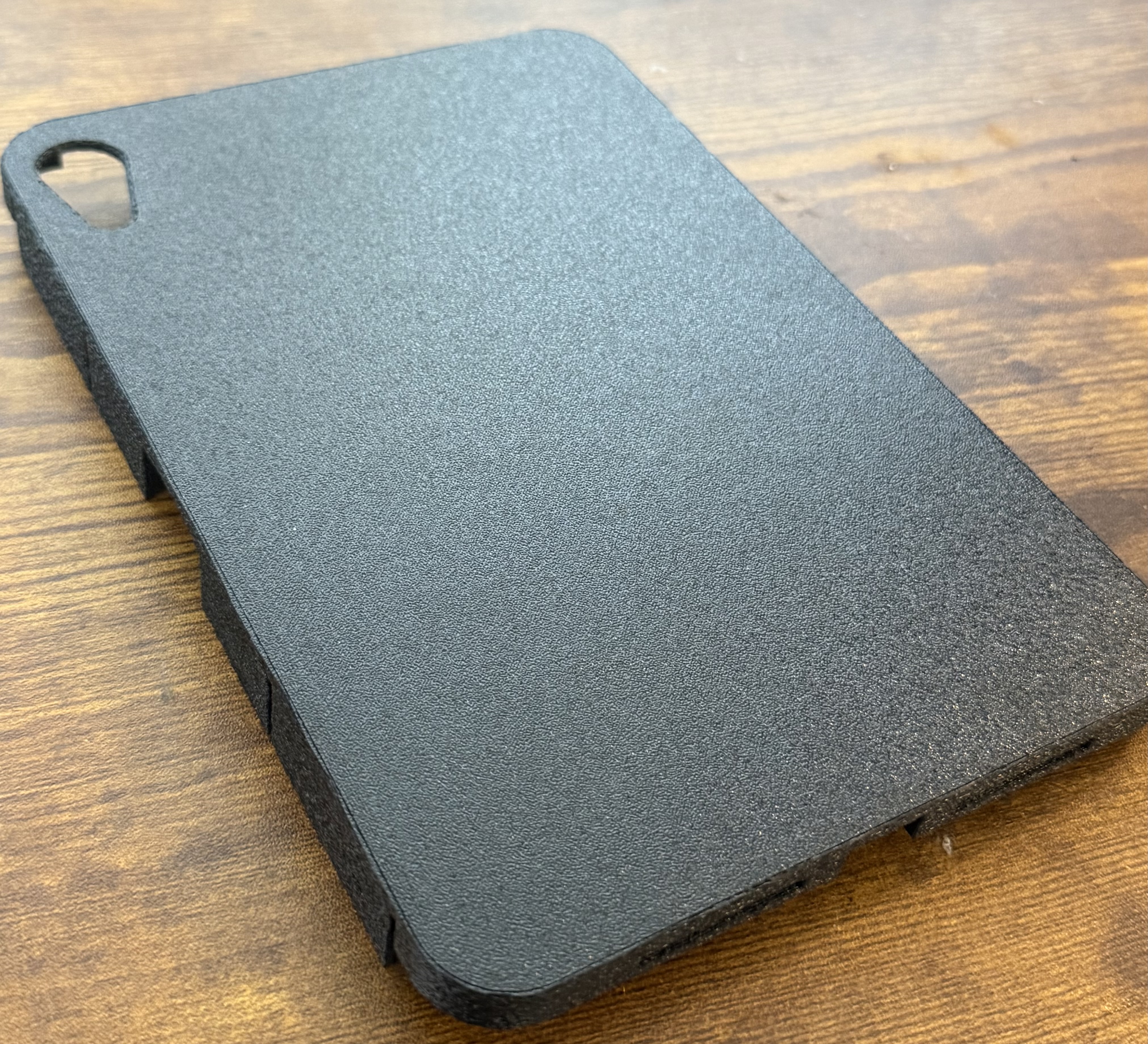 Black 3D-printed prototype case for an iPad Mini on a wood tabletop