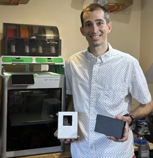 Stephen, owner of CoreyXYPrinting, standing beside his 3D printers and holding finished parts